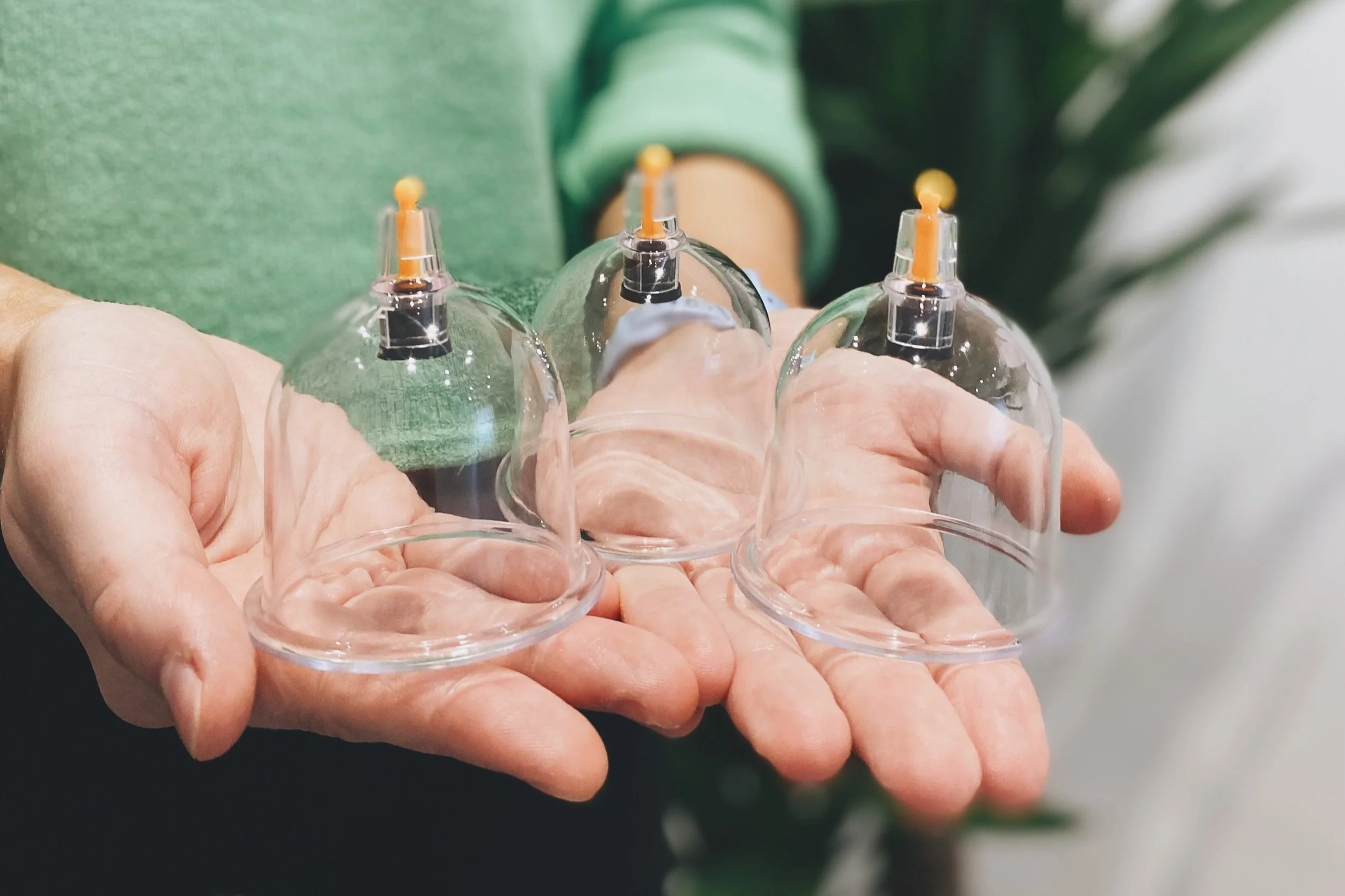 Person holding transparent cupping therapy cups used for muscle relaxation and detox treatment